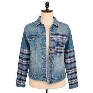 May include: A light blue denim jacket with plaid sleeves and a plaid pocket. The jacket has a button-up front, a collar, and gold stitching down the center. The sleeves and pocket feature a blue and white plaid pattern.