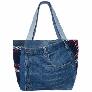 Puede incluir: Un bolso tote de mezclilla con un frente de mezclilla azul y un panel lateral de tela a cuadros. El bolso tiene un asa de mezclilla azul claro y un bolsillo en la parte delantera. La tela a cuadros presenta detalles en rojo y blanco.