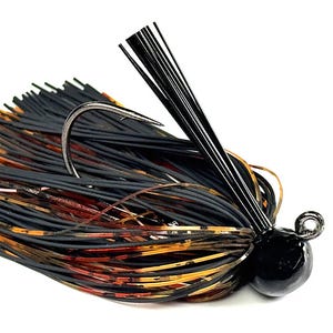 May include: A black and orange fishing jig with a curved hook and a black, rounded head. The jig features a skirt of black, orange, and brown strands, designed to attract fish. The hook is silver and the head is glossy.