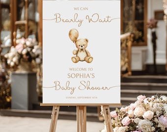 May include: A white sign on a wooden easel with the text "We Can Bearly Wait" and "Welcome to Sophia's Baby Shower". A watercolor illustration of a teddy bear holding a balloon is in the center. The date "Sunday, September 14th" is at the bottom.