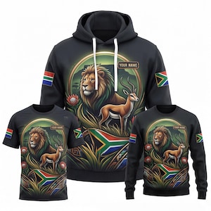 May include: A black hoodie, t-shirt, and sweatshirt set featuring a graphic of a lion and an antelope in a grassy landscape with the South African flag, protea flowers, and a rectangular box with the text YOUR NAME on each garment.
