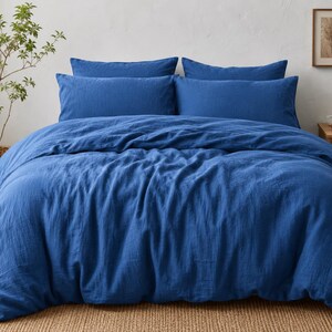 Royal blue linen duvet cover set styled on a modern bed with matching pillow covers in a cozy minimalist bedroom