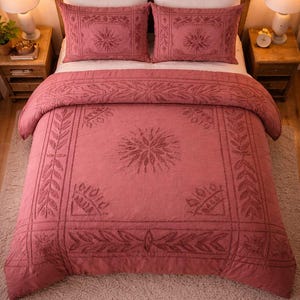 Puede incluir: Un edredón y dos fundas de almohada a juego de color rosa polvoriento con un diseño floral bordado. La ropa de cama está sobre una estructura de cama de madera, con dos mesitas de noche y lámparas a cada lado.