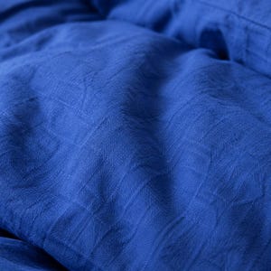 Royal blue linen duvet cover set styled on a modern bed with matching pillow covers in a cozy minimalist bedroom
