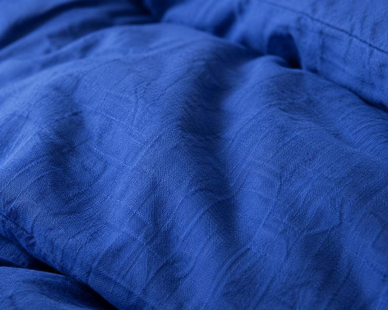 Royal blue linen duvet cover set styled on a modern bed with matching pillow covers in a cozy minimalist bedroom