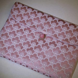 May include: A pink clutch bag with a repeating floral design in varying shades of pink and white. It features a flap closure fastened with a pink button and loop. The fabric has a slight sheen, giving it a luxurious look.