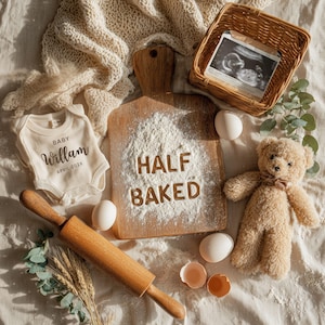 May include: A charming announcement scene featuring a baby onesie with the name "William" and the date "April 202X". A wooden cutting board with the words "HALF BAKED" in flour, a teddy bear, eggs, and a rolling pin are also present.