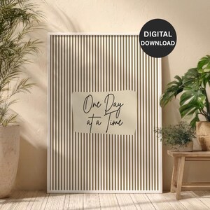 Puede incluir: Una impresión enmarcada con un patrón de rayas verticales en verde oliva y blanco. La impresión presenta el texto "One Day at a Time" en un estilo manuscrito. Un círculo negro con las palabras "DIGITAL DOWNLOAD" está en la esquina superior derecha.