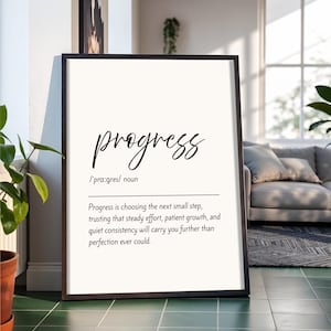 Puede incluir: Un cartel enmarcado con la palabra "progress" en escritura cursiva. La definición de progreso está debajo de la palabra, con un marco negro. El fondo es blanco.