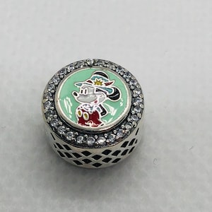 May include: A round silver charm bead featuring a central mint green enamel inlay with a cartoon mouse character wearing a hat. The circular border is set with clear stones, and the side of the bead has a black lattice pattern cut-out design.