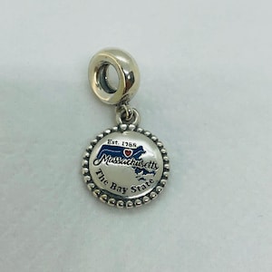 Könnte beinhalten: Ein silberner Charm-Anhänger mit einem runden Anhänger, der den Umriss des Bundesstaates Massachusetts in Blau, ein rotes Herz und den Text "Massachusetts The Bay State" zeigt. Der Charm ist an einer silbernen Schlaufe befestigt.