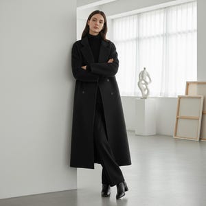 Black long wool coat for women with double-breasted design and minimalist modern aesthetic.