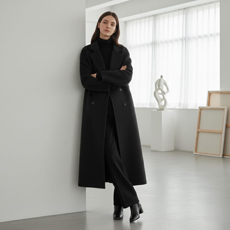 Black long wool coat for women with double-breasted design and minimalist modern aesthetic.