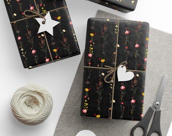 May include: Three wrapped gifts with black floral patterned paper, tied with twine and white tags. A ball of twine, scissors, and blank tags are also present, suggesting a gift-wrapping theme.