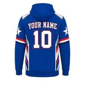 May include: A royal blue hoodie featuring the text YOUR NAME and the number 10 in white with red outlines on the back. The design includes white star graphics on the sleeves and red, white, and blue striped accents along the side panels.