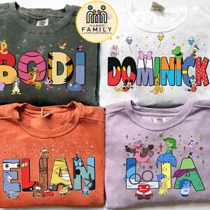May include: Four crew neck sweatshirts with personalised names and cartoon character designs. The sweatshirts are in green, white, orange, and purple. Each shirt features a different name in colourful block letters with cartoon characters.
