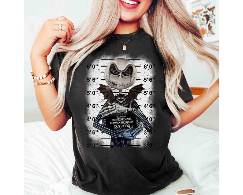 May include: Black t-shirt featuring a graphic of Jack Skellington from "The Nightmare Before Christmas" in a police lineup. The design includes the film's title and the date 13-10-1993. The shirt has a distressed look.