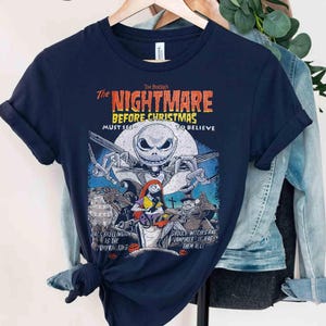 May include: A navy blue short-sleeve t-shirt featuring a graphic print from The Nightmare Before Christmas. The design includes Jack Skellington, Sally, and other characters with the text The Nightmare Before Christmas, Must See To Believe.
