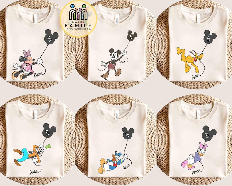 Puede incluir: Camisetas color crema con varios personajes de Disney sosteniendo globos negros con forma de Mickey Mouse con el n&uacute;mero 3. Cada camiseta tiene el nombre de un personaje escrito en cursiva. Los personajes incluyen Minnie, Mickey, Pluto, Goofy, Donald y Daisy.