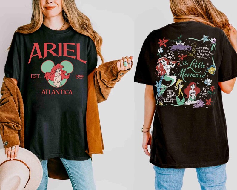 Puede incluir: Una camiseta negra con un gr&aacute;fico frontal que incluye el texto rojo ARIEL, EST. 1989, ATLANTICA y una ilustraci&oacute;n circular de Ariel. El gr&aacute;fico trasero muestra el texto The Little Mermaid, Ariel, Flounder e ilustraciones marinas.