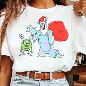 以下が含まれることがあります： 手書き風の「Welcome」の文字が入った、白く塗装された素朴な木製サイン。 表面は使い古したような加工が施され、隅には装飾的な花の要素があります。 背景はぼやけた木材の質感。