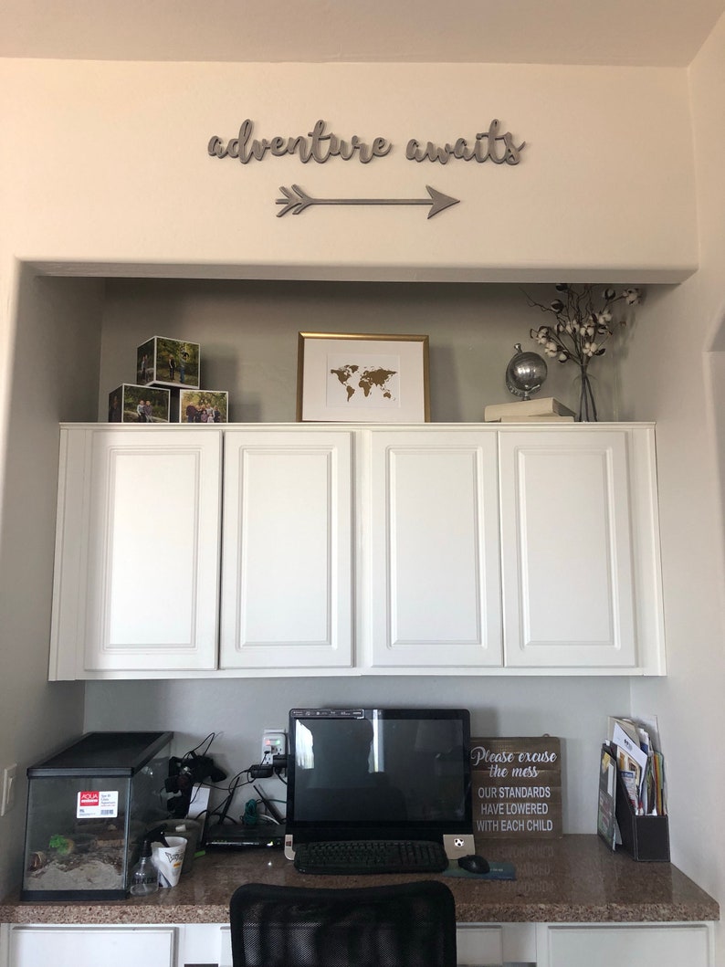 Adventure awaits signs with an arrow. The signs are made of 6mm thick plywood and are painted in Middle grey. They are suitable for wall decor