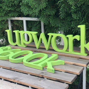 May include: Green wooden letters spelling "Upwork" and "600k" on a wooden surface.