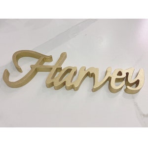 May include: Gold layered wooden name sign spelling "Harvey".
