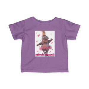 Pode incluir: Camiseta lilás com um gráfico de um hipopótamo dançando com tutu rosa, equilibrando rosquinhas. O texto "Hot-Mess-opotamus" está abaixo. A camiseta é de material macio, para crianças.