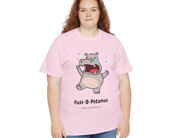 May include: A light pink t-shirt featuring a cartoon hippo with an open mouth and arms raised. The hippo is gray with a red mouth and a single tear. The text "Fuss-O-Potamus" and "DOG CLOTHING LLC" are printed below the hippo.