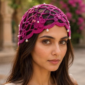May include: A vibrant magenta crochet cap featuring an intricate openwork lattice pattern, embellished with small white faux pearls at the intersections and along the scalloped bottom edge, accented with crocheted floral motifs throughout.