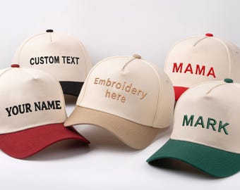 Op de afbeelding: Een verzameling baseballpetten in verschillende kleuren, elk met aangepaste tekst. De petten hebben een crèmekleurige kroon en een gekleurde klep, met tekst zoals "CUSTOM TEXT", "YOUR NAME", "MAMA" en "MARK".