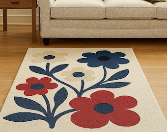 Puede incluir: Una alfombra rectangular con un diseño floral. La alfombra presenta grandes flores en colores rojo, azul y crema sobre un fondo neutro. Se encuentra sobre un suelo de madera, con un sofá y una mesa auxiliar en el fondo.