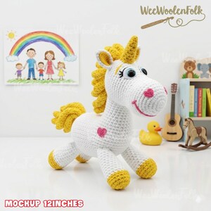 May include: A handmade white crochet unicorn with yellow mane, tail, and hooves. The unicorn has a pink heart on its side and a smiling face. The text "MOCKUP 12 INCHES" is at the bottom. The unicorn is approximately 12 inches tall.