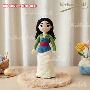 Może przedstawiać: Ręcznie robiona szydełkowa lalka, o wysokości około 35,5 cm, przedstawiająca postać z czarnymi włosami, ubraną w zielony top, niebiesko-czerwoną szarfę i kremową sp&oacute;dnicę. Lalka stoi na okrągłym, beżowym dywanie.