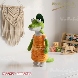 May include: A handmade crochet alligator doll, approximately 12 inches tall, wearing an orange dress with green sleeves and a green hat. The doll has white eyes and a white belly. The text "MOCKUP 12INCHES" is at the bottom.