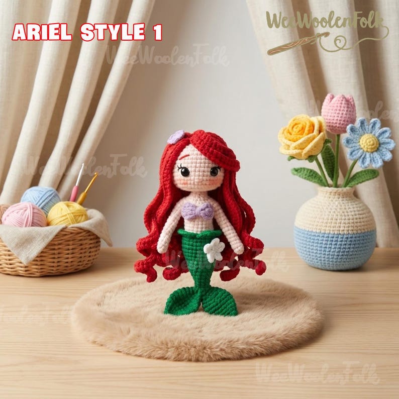 May include: Ariel Style 1 crochet doll with red hair, a purple top, and a green tail. The doll is displayed on a brown surface. A woven basket with yarn and a crochet hook is in the background. The text "We Woolen Folk" is visible.