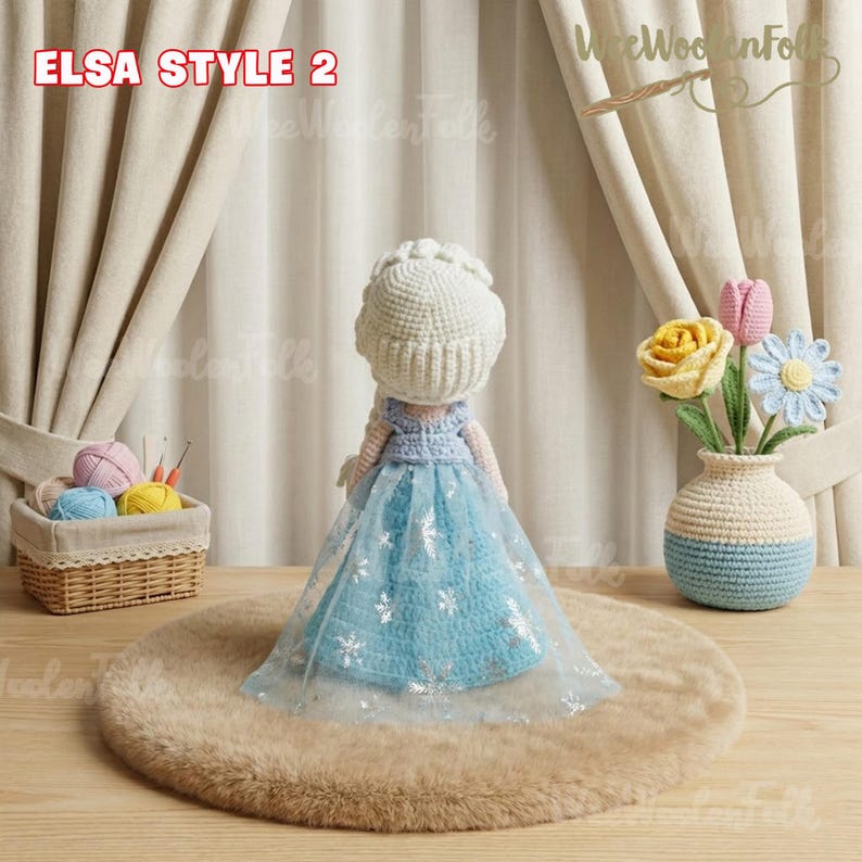 May include: A handmade crochet doll in the style of Elsa from Frozen, wearing a blue dress with silver snowflake accents and a white crocheted crown. The doll is displayed on a brown, fluffy rug. The text "ELSA STYLE 2" is visible.
