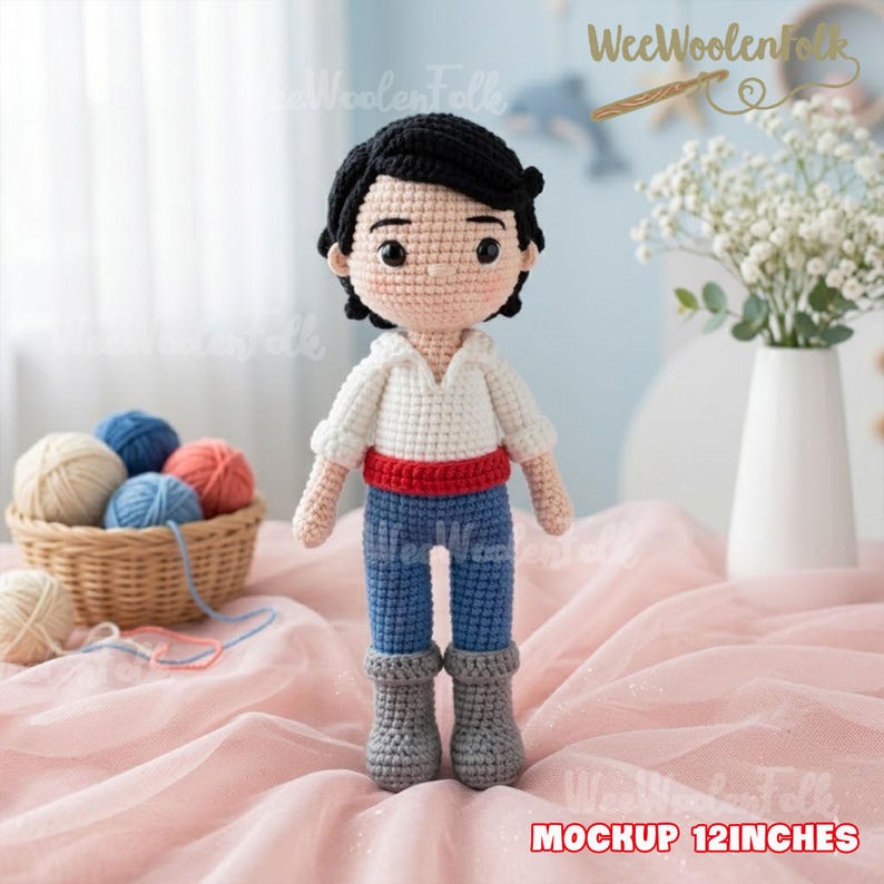 Puede incluir: Mu&ntilde;eca de ganchillo de 30 cm de un personaje de dibujos animados, con camisa blanca, pantal&oacute;n azul, cintur&oacute;n rojo y botas grises. La mu&ntilde;eca tiene pelo negro y est&aacute; delante de una cesta de lana y un jarr&oacute;n con flores blancas.