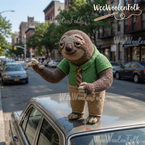 May include: A handmade crochet sloth doll, wearing a green shirt and a striped tie, stands on a car. The sloth has brown and tan coloring, with detailed facial features. The background shows a city street with parked cars and buildings.