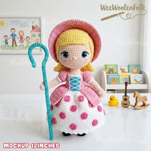 May include: A handmade crochet doll, approximately 12 inches tall, dressed in a pink and white polka-dot dress and a matching bonnet. The doll has blonde hair, blue eyes, and is holding a turquoise shepherd's crook. The doll is a Bo Peep character.