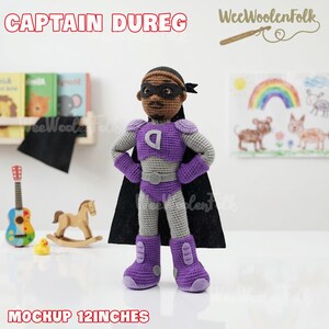 Puede incluir: Mu&ntilde;eco de superh&eacute;roe de ganchillo hecho a mano, de aproximadamente 30 cm de altura, con un disfraz morado y gris y una capa negra. El mu&ntilde;eco tiene una m&aacute;scara negra y el texto "CAPTAIN DUREG" est&aacute; encima.