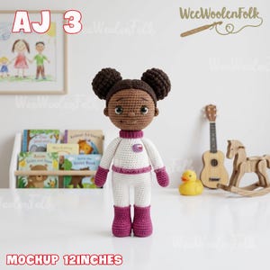 Puede incluir: Mu&ntilde;eca de ganchillo hecha a mano, de aproximadamente 30 cm de altura, vestida con un traje de astronauta blanco y morado. La mu&ntilde;eca tiene piel morena, cabello oscuro en dos mo&ntilde;os, frente a una estanter&iacute;a y una guitarra.