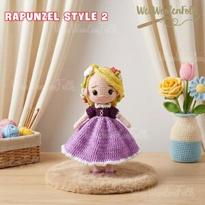May include: A handmade crochet doll in the style of Rapunzel, with blonde yarn hair and a purple dress. The doll has a white collar and is standing on a small, round, brown rug. The text "RAPUNZEL STYLE 2" is visible in the image.