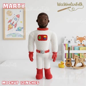 Puede incluir: Mu&ntilde;eco de astronauta hecho a mano, tejido a ganchillo, de unos 30 cm de altura, con un traje espacial blanco y detalles rojos. El mu&ntilde;eco tiene la cabeza marr&oacute;n y lleva guantes y botas rojas. Se muestra el nombre "Marty".