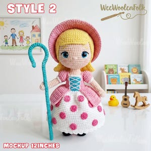 May include: A handmade crochet doll, styled as a character with a pink dress, hat, and a blue shepherd's crook. The doll is approximately 12 inches tall. The doll has blonde hair and blue eyes. The dress has white fabric with pink polka dots.