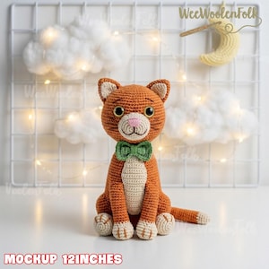 May include: A crocheted orange cat toy with a cream-colored chest, paws, and muzzle, featuring a green bow tie, black eyes, and a pink nose. The cat is 12 inches tall. The text 'WeeWoolenFolk' and 'MOCKUP 12INCHES' are visible in the image.