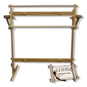 May include: A light-colored wooden needlework floor stand featuring adjustable horizontal bars and side knobs. A smaller, separate E-Z STITCH Needlework Frames display piece with a red thread accent is positioned in the lower right corner.