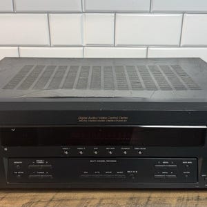 May include: A black Sony Digital Audio/Video Control Center receiver featuring a large master volume knob on the right, a central display panel, and various control buttons. The front panel includes the Sony logo, input labels, and DTS logos.