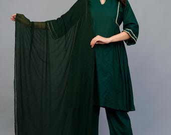 May include: A dark green, three-piece outfit featuring a tunic top, wide-leg pants, and a sheer scarf. The tunic has a V-neck and three-quarter sleeves, all trimmed with gold-colored detailing. The pants also have gold trim at the hem.